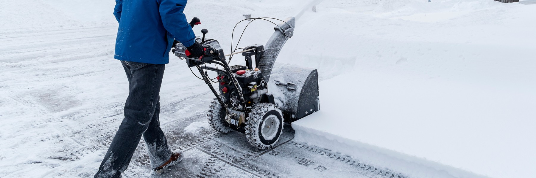 Snow blower clearing a snowy residential driveway