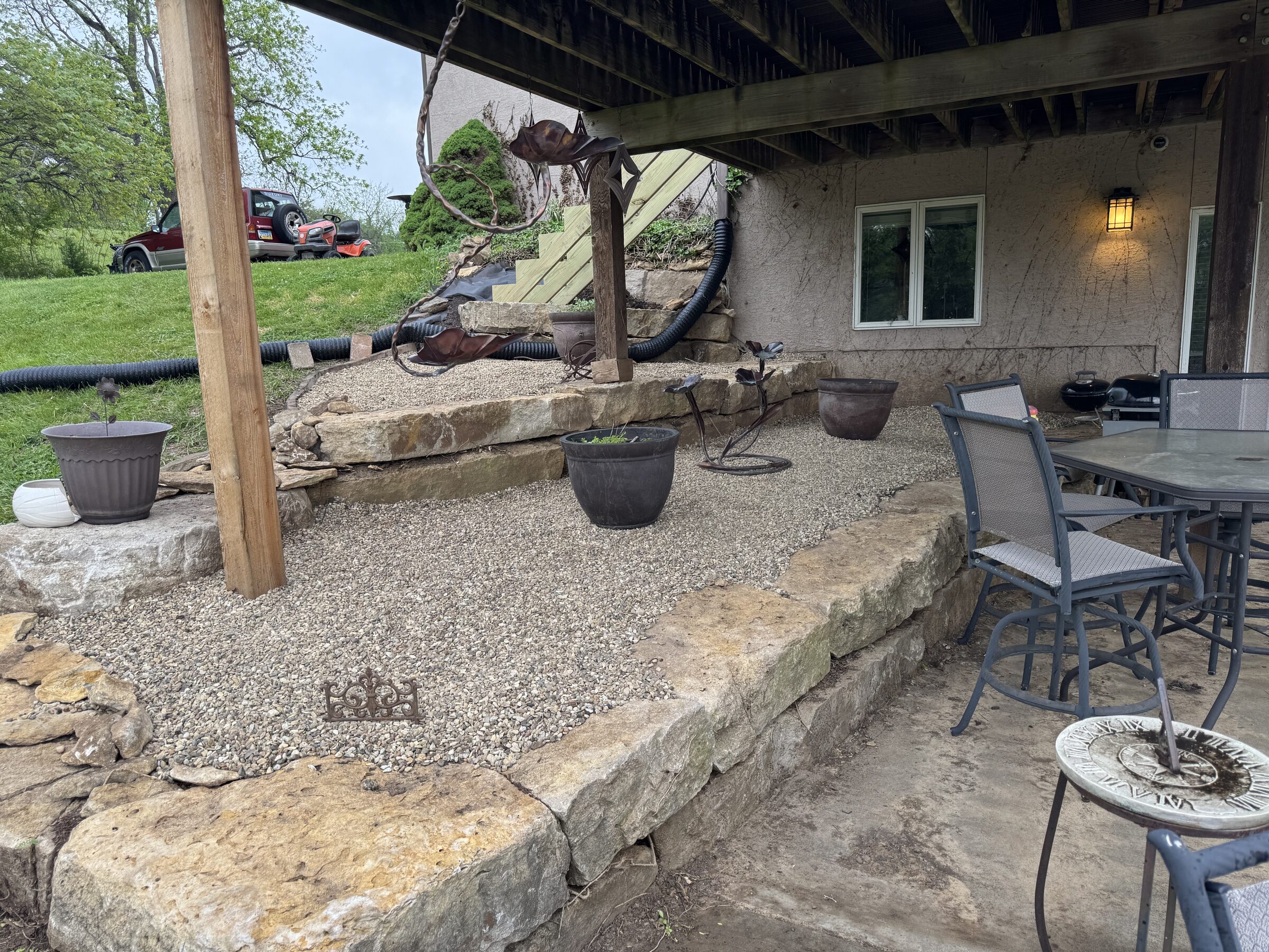 Stone patio and gravel beds under a deck, cleared of overgrowth by Twin Cut Services